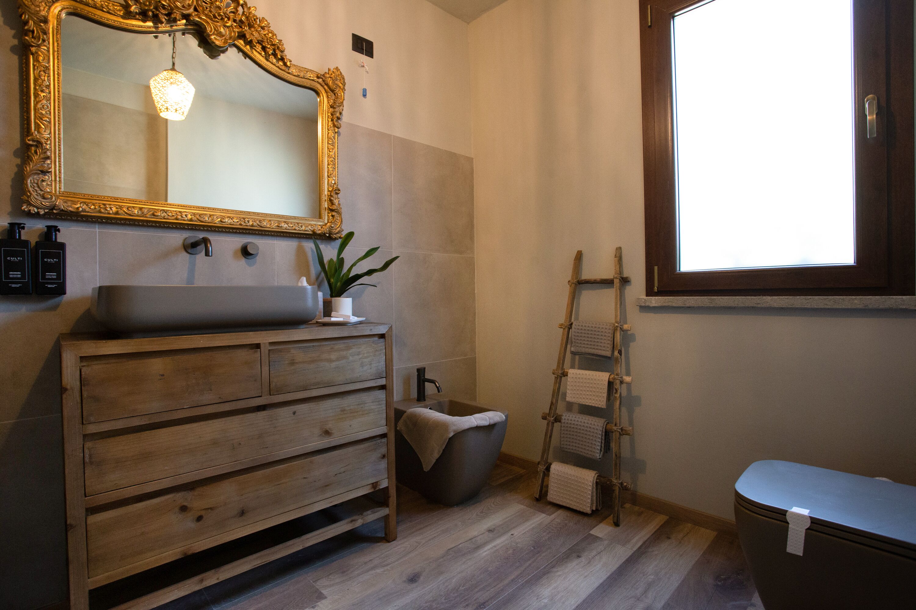 Een badkamer met een houten wastafel, een grote spiegel, een badkuip en een handdoekhouder.