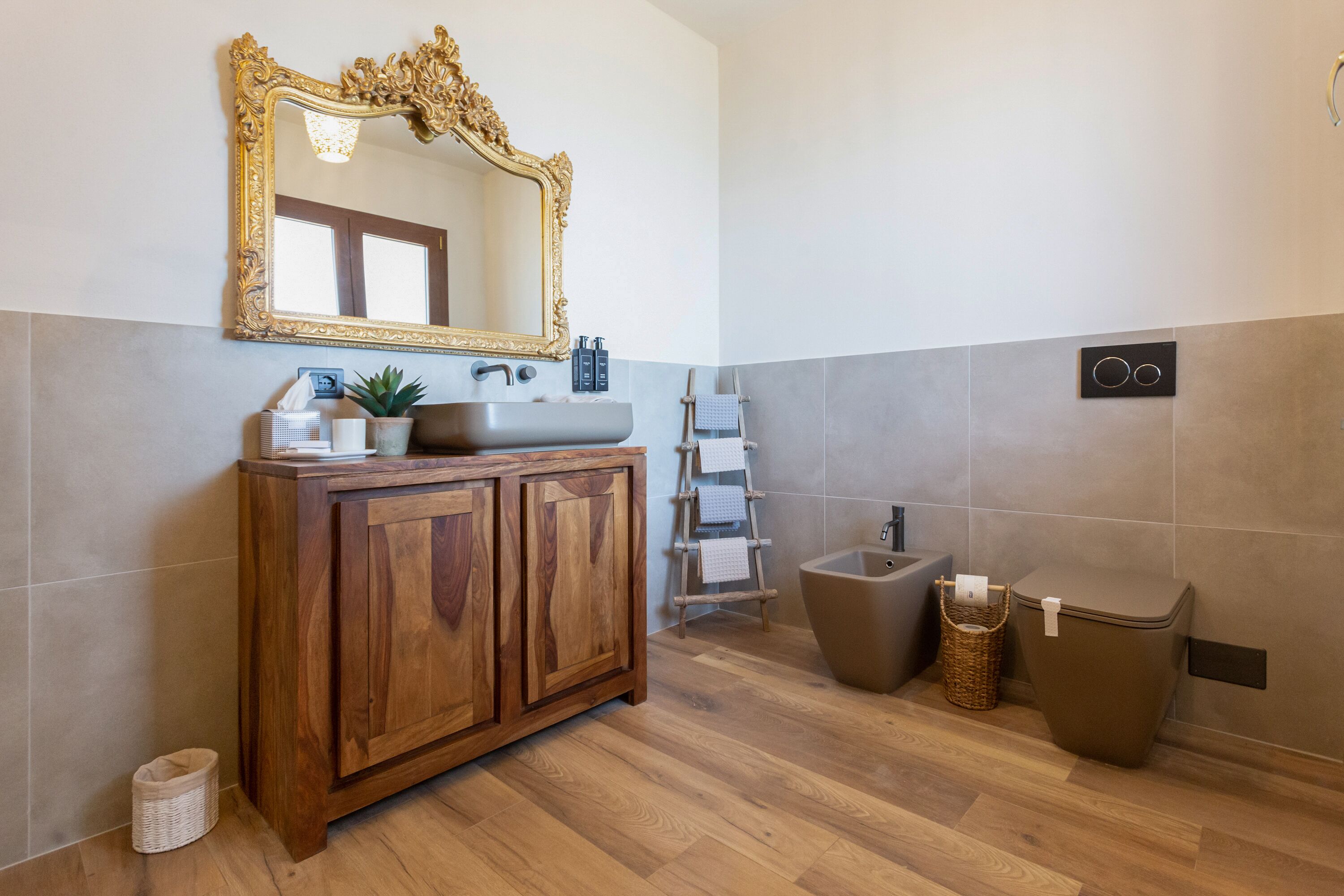 Ein Badezimmer mit einem Holzkosmetikschrank, einem großen Spiegel, einem Waschbecken, einer Toilette und einem Handtuchhalter.