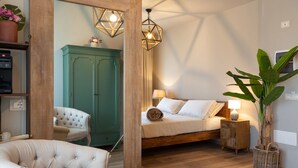 A bedroom with a bed, a nightstand, a lamp, a chair, a wardrobe, and a potted plant. - Relais San Baio (Cecina)
