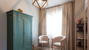 A room with a green wardrobe, two upholstered chairs, a wooden floor, and a window with curtains. - Relais San Baio (Cecina)