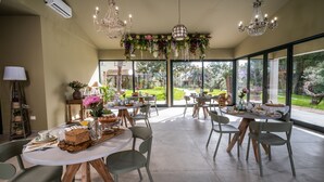 A spacious dining area with round tables, green chairs, and hanging floral decorations. - Relais San Baio (Cecina)