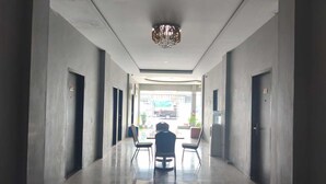 A hallway with a chandelier, doors, and a view of the outside. - Collection O near Lampung City Mall formerly Royal Guesthouse (Bandar Lampung)