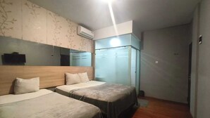 A hotel room with two beds, a wardrobe, a mirror, and an air conditioning unit. - Collection O near Lampung City Mall formerly Royal Guesthouse (Bandar Lampung)