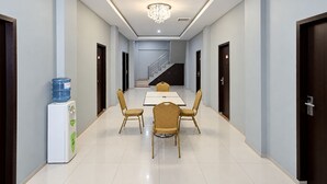 Een hotelgang met een eetgedeelte, inclusief een tafel, stoelen, een waterdispenser en een trap naar een andere verdieping.