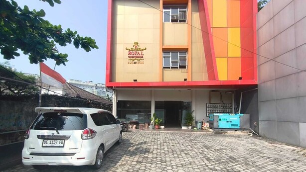 A building with a sign reading 'ROYAL QUESTHOUSE' and a white car parked in front. - Collection O near Lampung City Mall formerly Royal Guesthouse (Bandar Lampung)