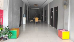 A hallway with a staircase, a water dispenser, and a Coca-Cola advertisement. - Collection O near Lampung City Mall formerly Royal Guesthouse (Bandar Lampung)
