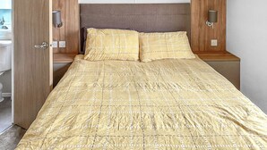 Un lit avec une couvre-lit à motifs, une tête de lit en bois, des lampes de chevet et une armoire en bois.