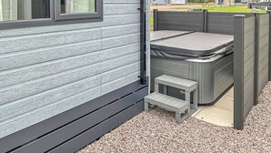 Un petit espace extérieur aménagé en patio, avec une table et des bancs, le tout entouré d’une clôture en bois.