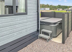 A small outdoor patio area with a table and benches, surrounded by a wooden fence.