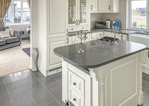 A modern kitchen with white cabinetry, a granite countertop, and a built-in oven.