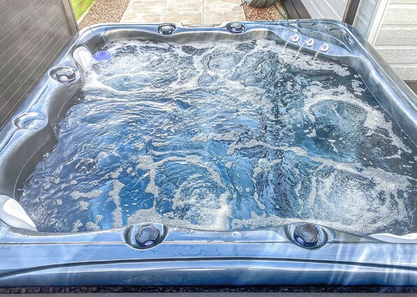 Een hottub met meerdere jets, omgeven door een houten terras.
