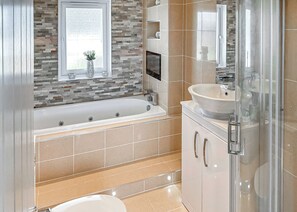 Een moderne badkamer met een bad, wastafel en douche.
