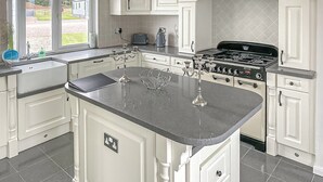 A kitchen with a large island, white cabinetry, a stove, and a view of the outdoors. - 2 bedroom accommodation in Laurenkirk (Laurenkirk)