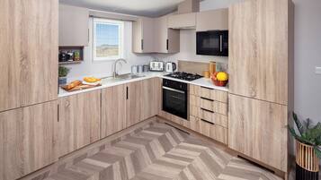 Une cuisine moderne avec des meubles en bois, un four à micro-ondes, une cuisinière à gaz et un plancher à motifs en chevrons.
