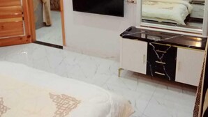 A bedroom with a bed, a TV mounted on the wall, a bedside table, and a wardrobe. - Al Rehman Palace 1 (Lahore)
