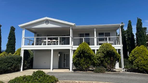 A two-story house with a balcony, a garage, and well-maintained landscaping.