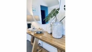 A wooden console table with a mirror, a lamp, and decorative items including a plant and a vase.