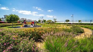 Ein Spielplatz mit Rutschen und einem eingezäunten Bereich, der gepflegte Gärten und Wege bietet.