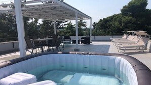 Ein Außenwhirlpool mit Liegestühlen und einer überdachten Sitzgruppe.
