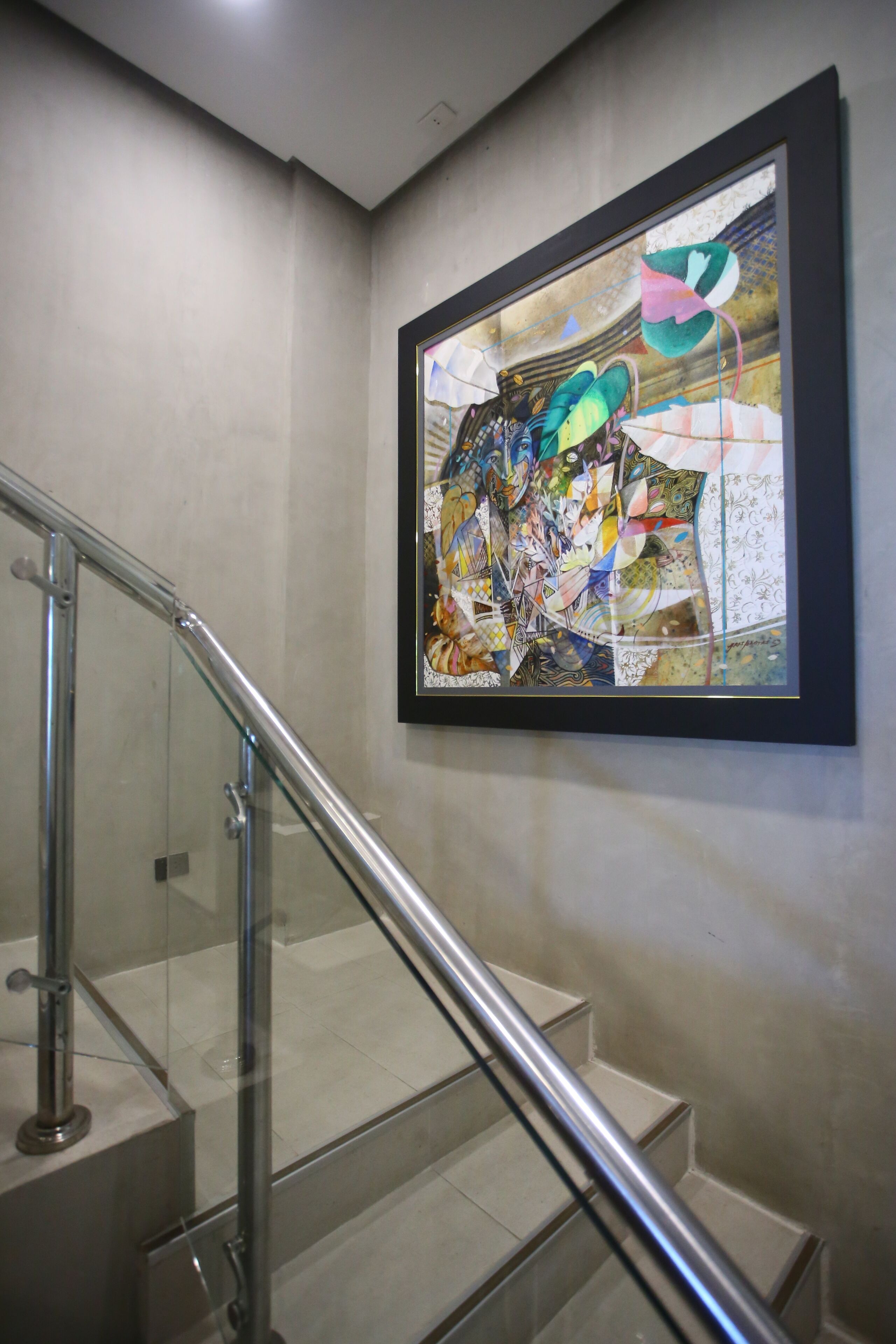 A staircase with glass railings and a colorful abstract painting on the wall.