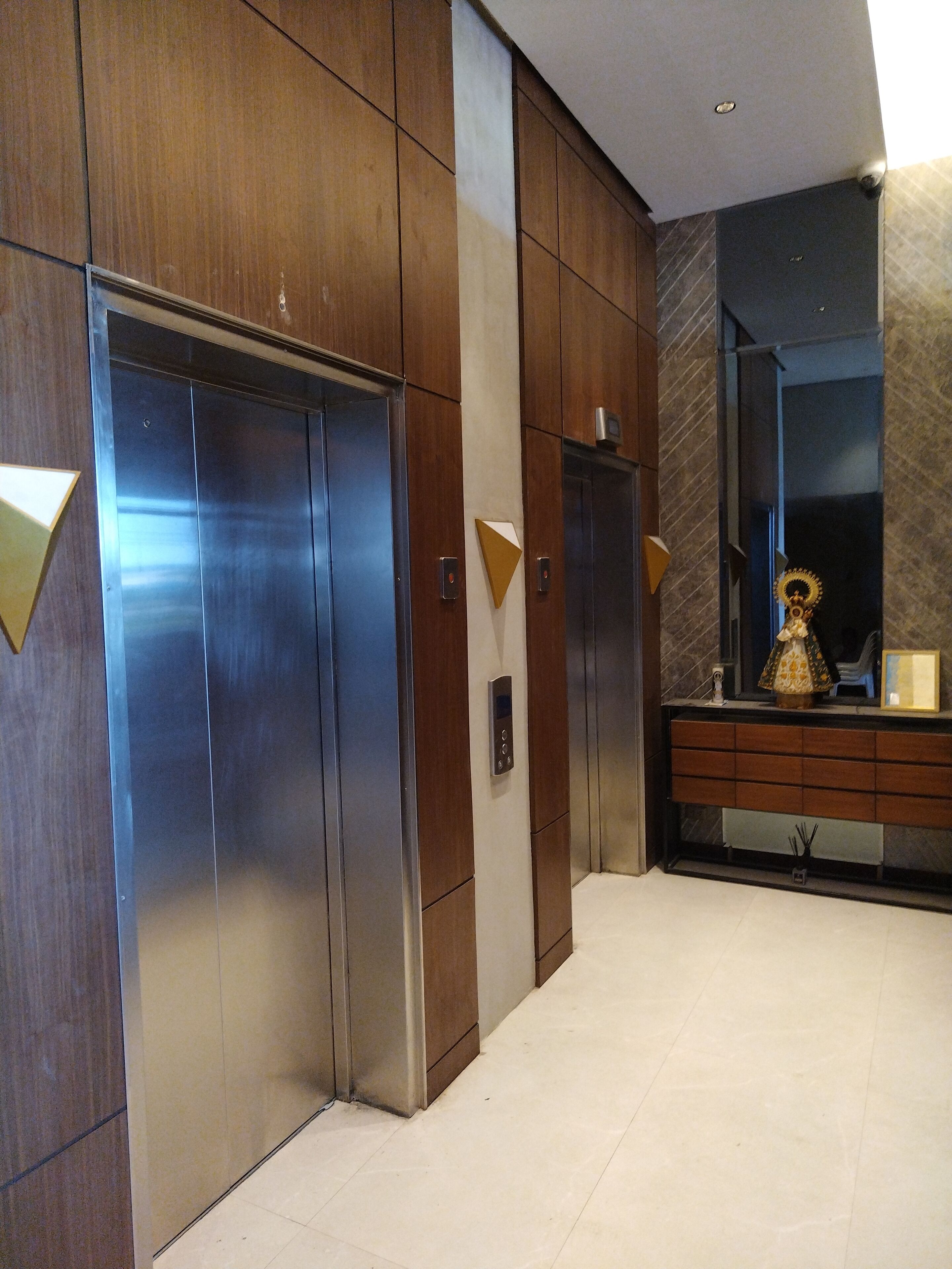 A modern elevator with a control panel and a wooden panel design.