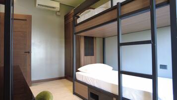 A bunk bed with a wooden frame, a small storage drawer, and a mesh panel on the wall.