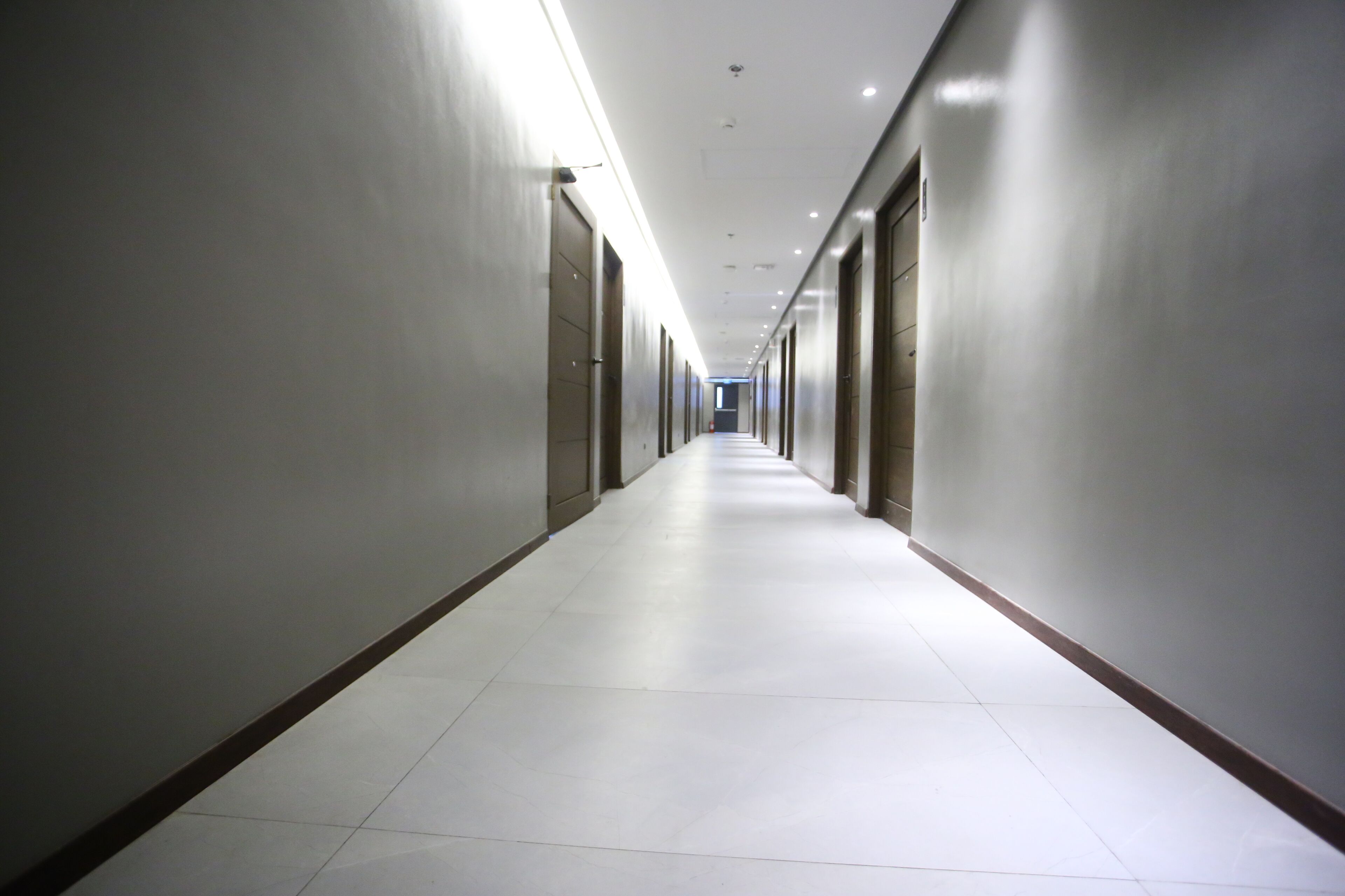 A long, narrow hallway with doors on both sides, lined with recessed lighting.
