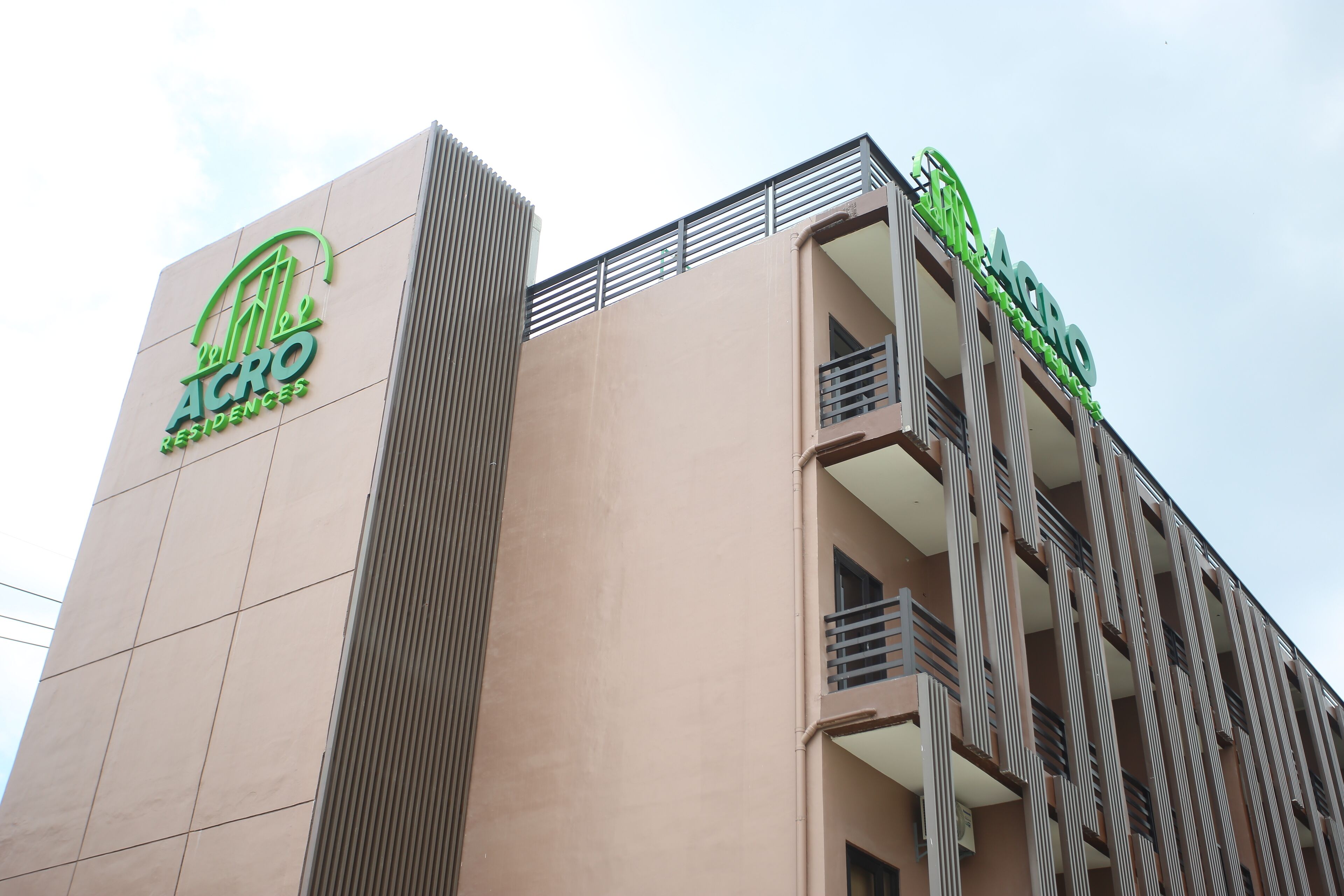 Um edifício com um logotipo verde destacado e a inscrição "ACRO RESIDENCES" na fachada.