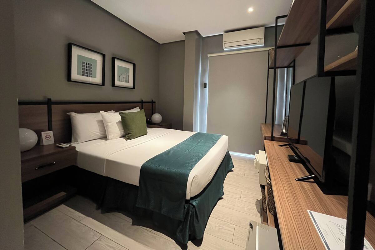 Een moderne hotelkamer met een groot bed, een bureau en een televisie.