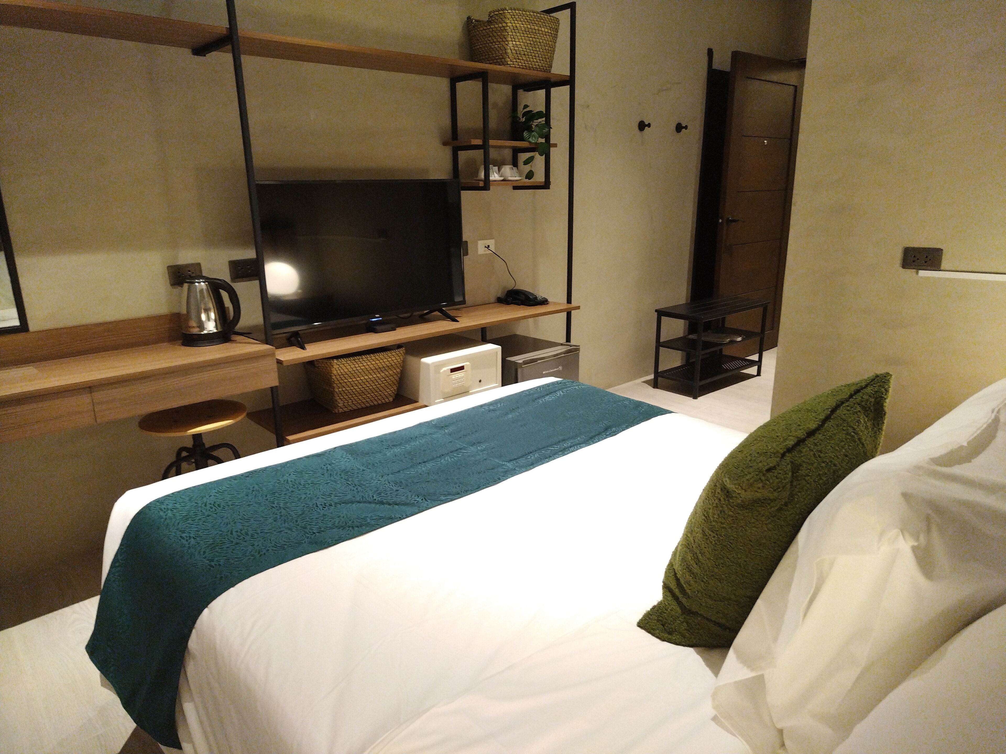 A hotel room with a bed, a television, a coffee maker, and a desk with a computer.