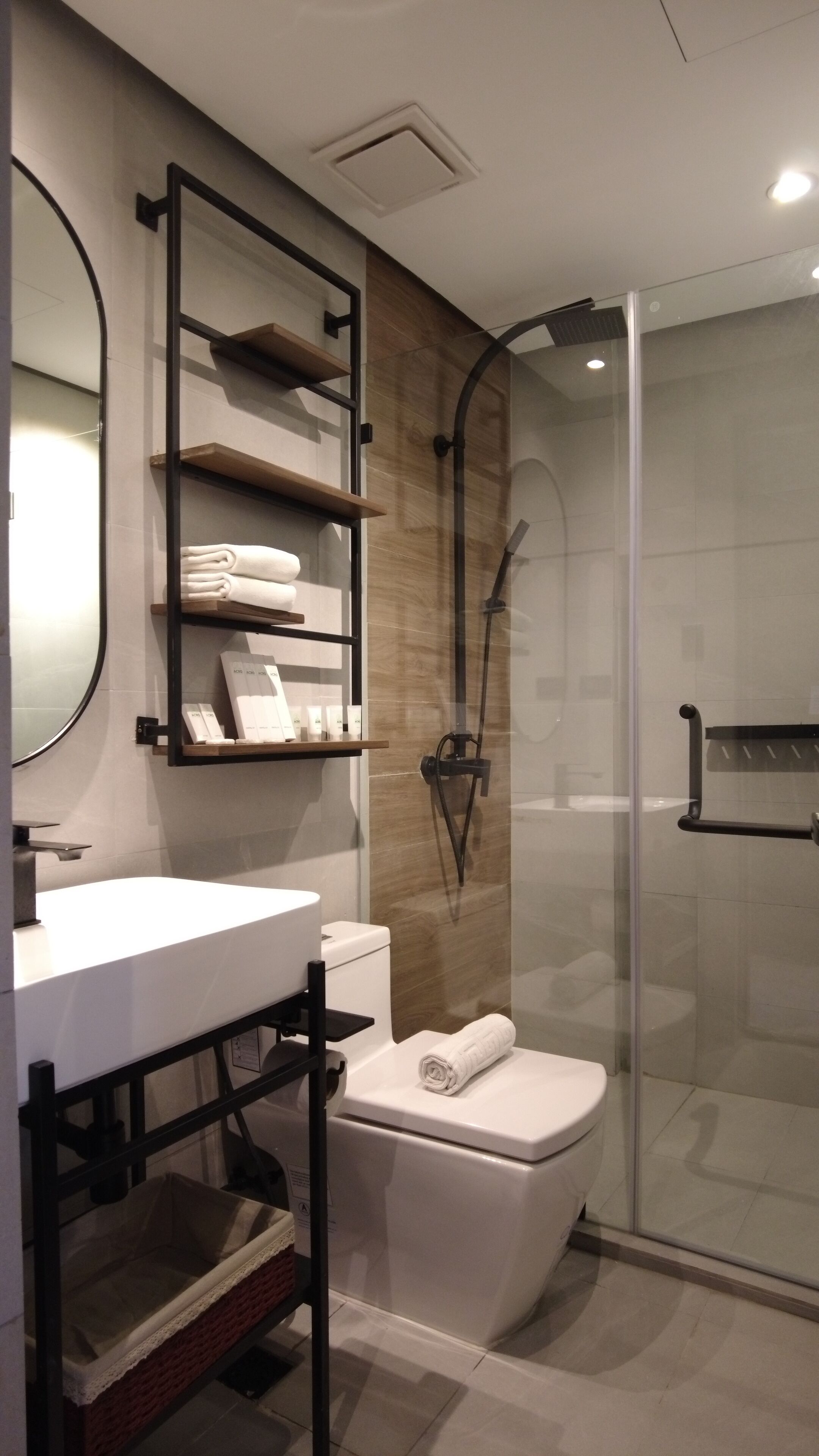 A modern bathroom with a glass shower enclosure, a white toilet, and a vanity with shelves.