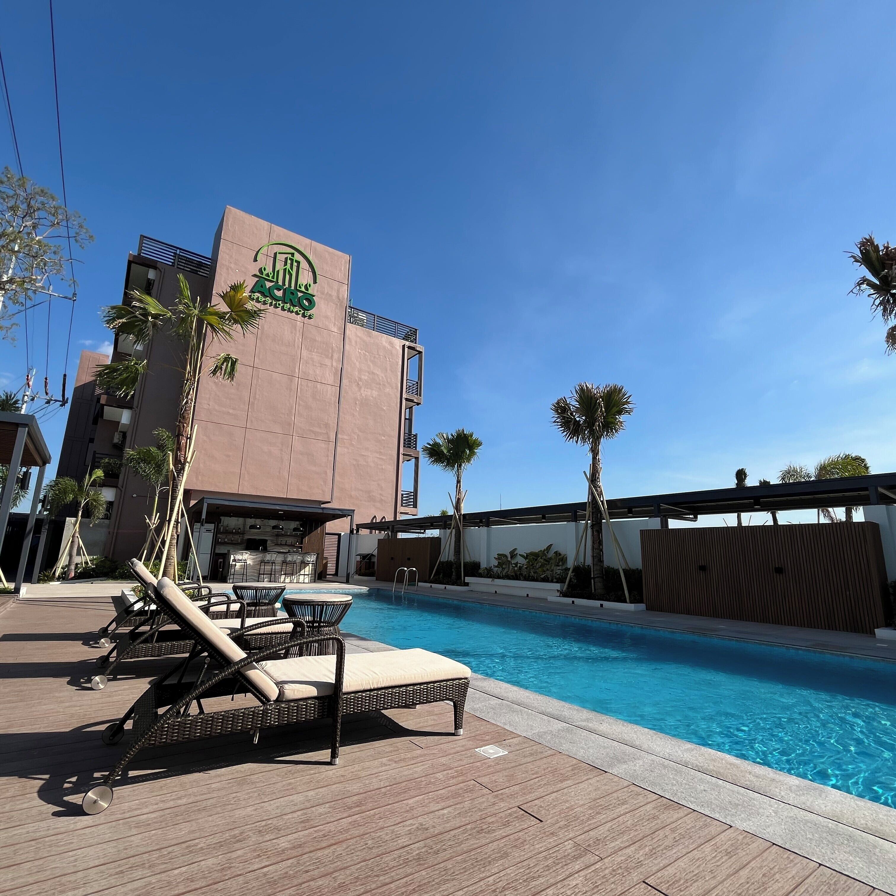 Un hôtel doté d’une piscine, de chaises longues et de palmiers.