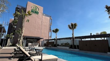 Un hôtel doté d’une piscine, de chaises longues et de palmiers.
