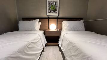 A hotel room with two beds, a nightstand with a lamp, and a framed picture on the wall.