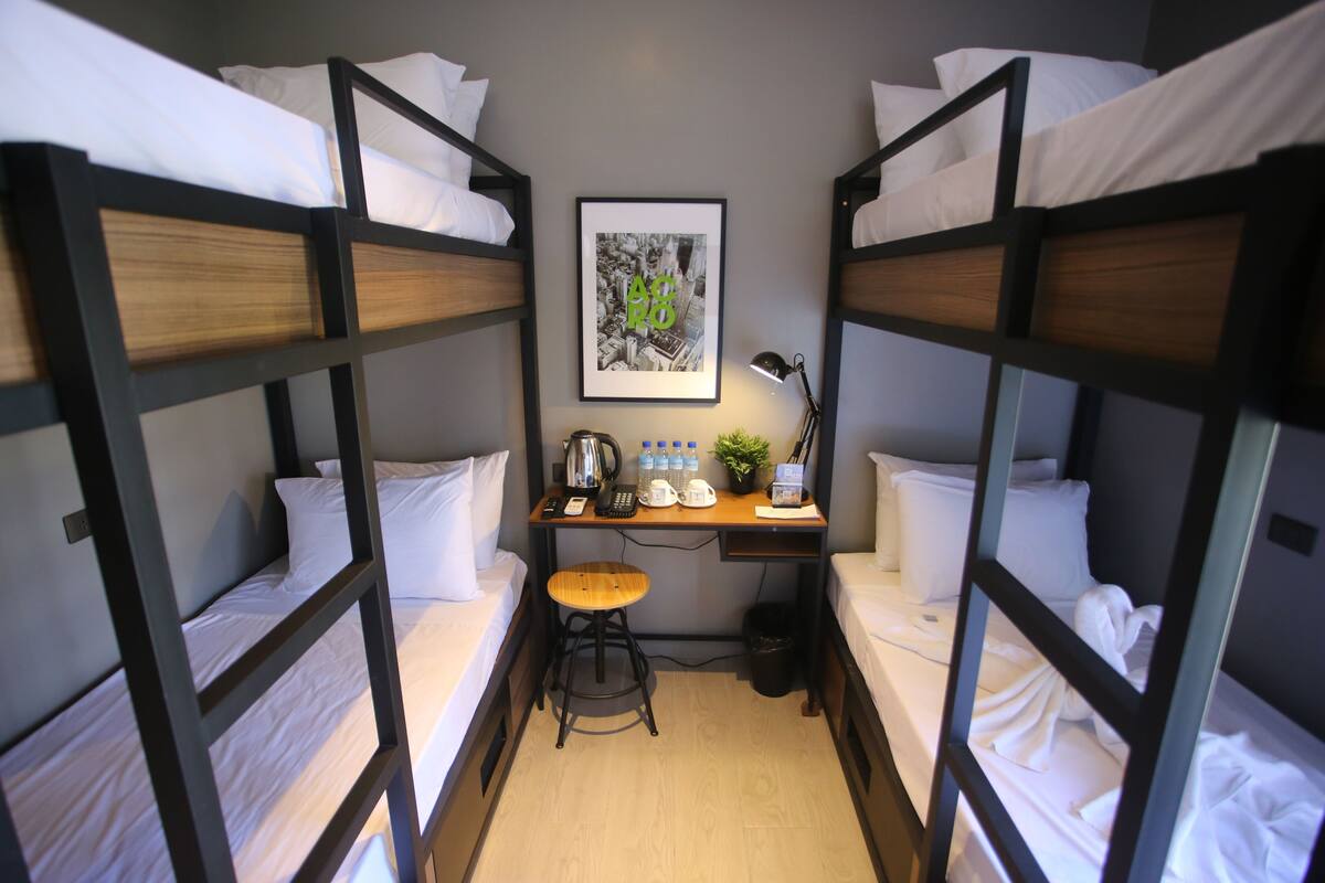 Een slaapkamer met een stapelbed, een bureau, een stoel en een ingelijste foto aan de muur.