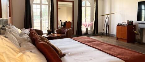 A hotel room with a large bed, a desk, a chair, a mirror, and a telescope.