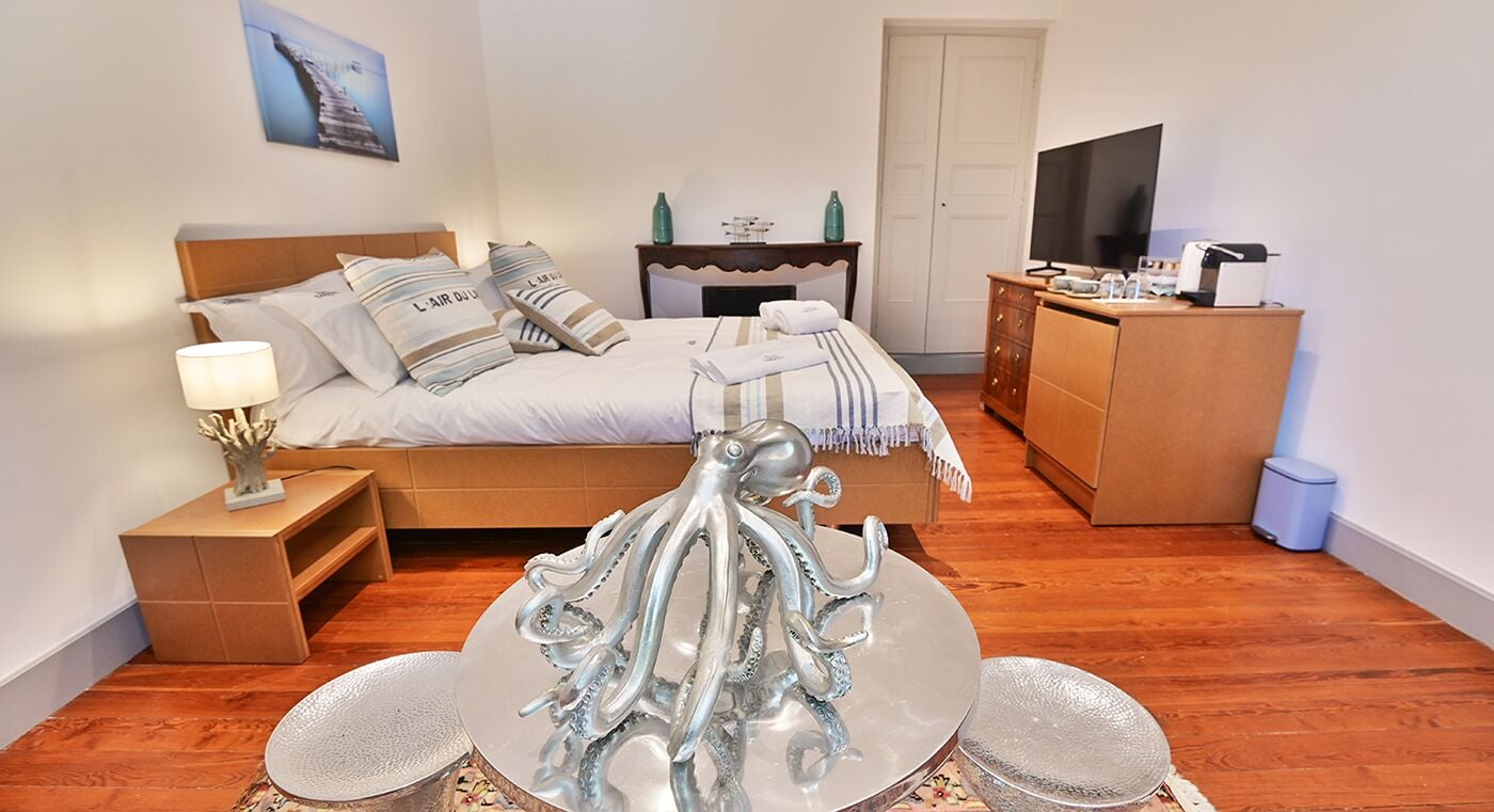 A bedroom with a bed, a dresser, a television, and a decorative octopus sculpture.