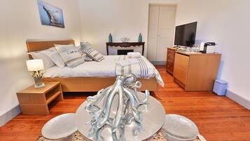 A bedroom with a bed, a dresser, a television, and a decorative octopus sculpture.