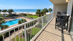 A balcony with a view of a swimming pool and beach.