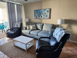 Una sala de estar con un sofá, dos sillones, una mesa de centro y un cuadro en la pared.