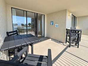 An outdoor patio with a table and chairs, a glass door leading to a pool area, and a wall with two starfish decorations.