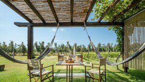 Un hamac installé dans un coin du jardin, avec une table et des chaises, le tout sous une pergola.