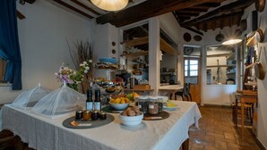 Un coin repas avec une table dressée pour le repas, entouré d’étagères de cuisine et surmonté d’un plafond rustique.