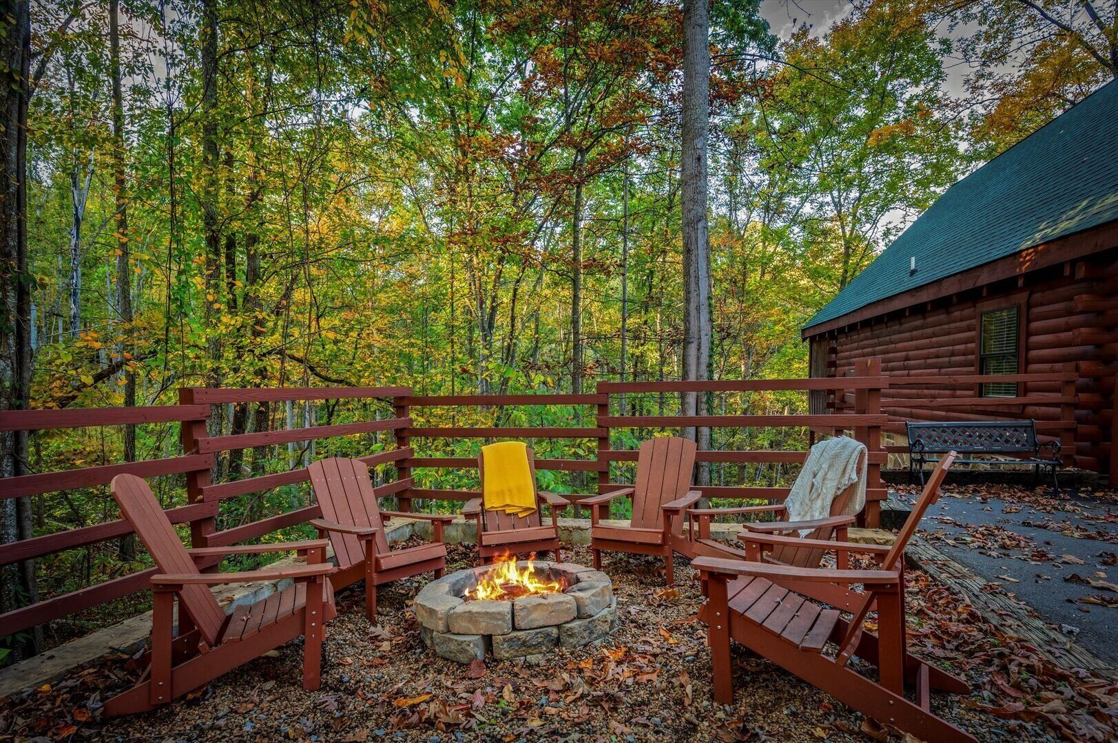 Una terraza de madera con sillas Adirondack y un hogar a fuego de piedra.