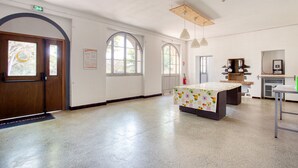 A spacious room with a large table, arched windows, and a kitchenette area. - Auberge de Fréjus Saint-Raphael - Hostel (Fréjus)