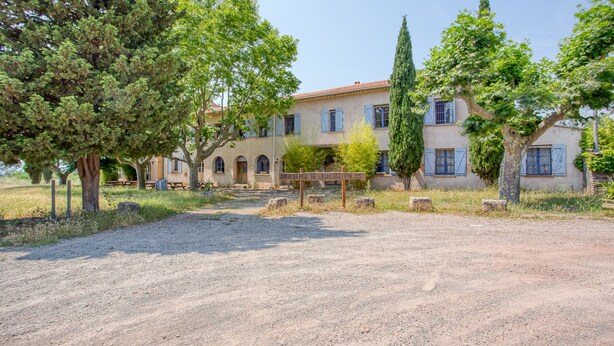 A rustic building with a gravel driveway, surrounded by trees and a clear sky. - Auberge de Fréjus Saint-Raphael - Hostel (Fréjus)