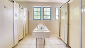 A long, narrow bathroom with two sinks, a window, and multiple toilet stalls. - Auberge de Fréjus Saint-Raphael - Hostel (Fréjus)