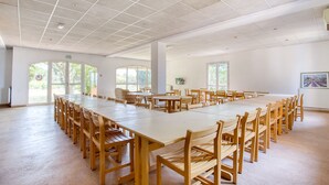 A large conference room with long tables and chairs, large windows, and a tiled ceiling. - Auberge de Fréjus Saint-Raphael - Hostel (Fréjus)