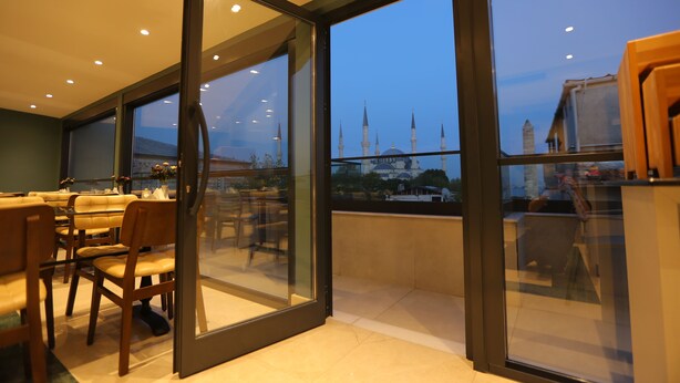A modern dining area with a view of a mosque through large windows. - Haci Bayram Hotel (Istanbul)