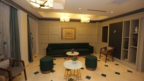 A modern lounge with a green sofa, two round tables with potted plants, and a decorative ceiling light fixture. - Haci Bayram Hotel (Istanbul)